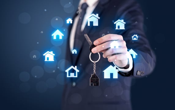 Businessman in suit holding keys with house graphics around and dark background