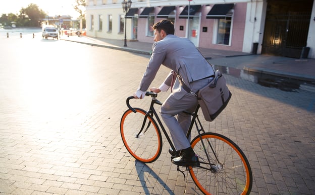 Businessman riding bicycle to work on urban street in morning