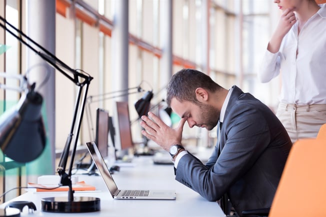 frustrated business man working on laptop computer at office, likely to have made a mistake